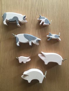 several small wooden animals are on a table with one pig and the other pig is laying down