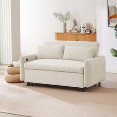 a living room with a white couch and potted plants on the side table in front of it