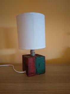 a wooden block with a white lamp on top of it sitting on a table next to a wall