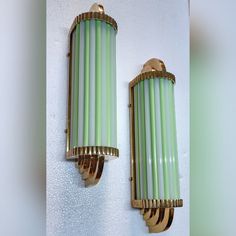 two green and gold sconces mounted on the wall next to eachother