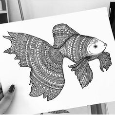 a person holding up a drawing of a fish with intricate designs on it's body