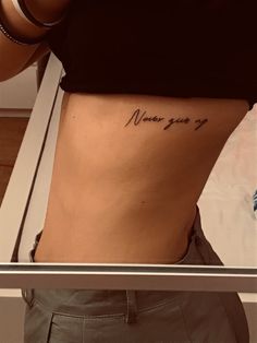 a woman's lower back tattoo with the words never you so written on it