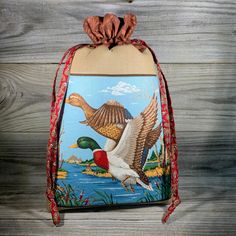 a bag with a painting of two birds flying over the water on it's side