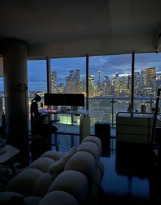 a living room filled with furniture and large windows overlooking the city skyline at night time