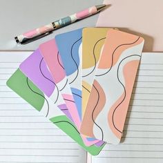 four notebooks with different colored lines on them next to a pen and paper pad