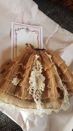 an old fashioned dress is sitting on the ground next to a card and some papers