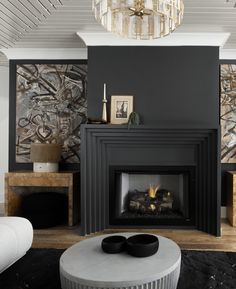 a living room with a fire place and chandelier hanging from the ceiling above it