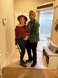 a woman standing next to a man wearing a mask on his face in a hallway