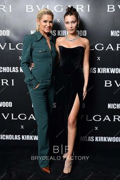 two women standing next to each other on a black carpet