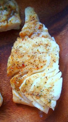 some kind of food sitting on top of a wooden cutting board with seasoning sprinkled on it