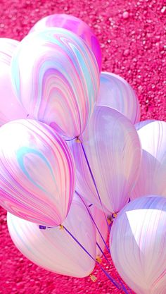 a bunch of white balloons sitting on top of a pink ground next to each other