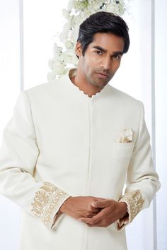 This ivory sherwani set features kiran dori embroidery on the cuffs and a stepper collar detail on a matka silk base. This ensemble is paired with a cotton silk kurta and a stretchable cotton silk trouser. Complimenting footwear is also available.From Seema Gujral's Tuscan Summer collection. DELIVERY TIMEPlease allow 8-12 weeks for your outfit to arrive.FABRIC DETAILSMatka SilkProfessional cleaning only. Off White Naqshi Bandhgala For Festive Occasions, Off White Bandhgala With Naqshi For Festive Occasions, Eid Fitted Kurta With Embroidered Cuffs, Cream Sherwani With Chikankari Embroidery And Long Sleeves, Cream Long Sleeve Sherwani With Chikankari Embroidery, Festive Off White Bandhgala With Naqshi, Off White Bandhgala With Naqshi For Diwali, Off White Naqshi Bandhgala For Diwali, Fitted Sets With Embroidered Cuffs For Festive Occasions