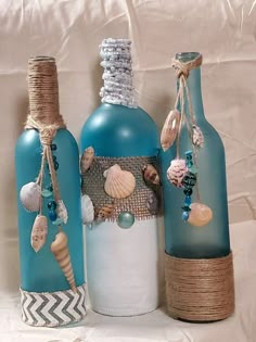 three bottles with seashells on them are sitting next to each other and tied together