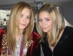 two beautiful young women sitting in the back seat of a car, one with blonde hair