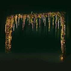 an archway decorated with flowers and lights in the dark night light up for a wedding ceremony