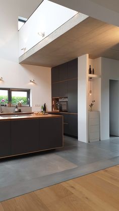 an open kitchen and living room with wood flooring on the side, along with skylights