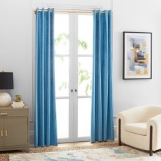 a living room with blue curtains and a white chair