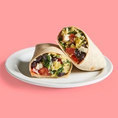 two burritos on a white plate against a pink background