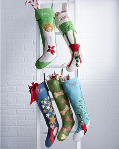 christmas stockings hanging from a rack in front of a brick wall