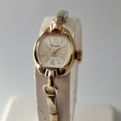 A very elegant MANOIR SWISS Made Ladies Cocktail Watch dating to the Mid 1960's. The gold plated case is in very good condition, elegant in its design, it measures 16mm in width excluding the crown and is 27.5mm in length from lug to lug. The dial and hands are in very fine condition. The original crystal has been hand polished to a shine. Case back is stainless steel. The SWISS made movement is a very good quality FHF Caliber 69, a 17 Jewel High Beat (21,600 BPH) manual wind movement, which we Retro Gold Watch With Polished Finish, Retro Gold Watches With Polished Finish, Gold Retro Watch With Polished Finish, Retro Gold Collectible Watches, Vintage Gold Hallmarked Jewelry And Watches, Vintage Gold Watches For Formal Occasions, Vintage Gold Jewelry And Watches For Anniversary, Cocktail Watch, Wind Movement