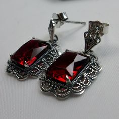 Simulated Red Ruby Solid Sterling Silver Earrings Short Festoon Design#E8z (shorter version) These Victorian reproduction estate earrings are solid sterling silver. These filigree earrings have stunning simulated red ruby gemstones. Each stunning gem is 10mm x 8mm x 5mm in dimension. The earrings are approximately 1/2" x 1" (13mm x 23mm). The unique earrings are marked 925 for solid sterling silver. These lovely earrings were refashioned from an antique Victorian cameo necklace. Quintessentially Classic Red Earrings For Party, Handmade Red Earrings For Formal Occasions, Classic Red Party Earrings, Red Classic Jewelry With Matching Earrings, Classic Red Jewelry With Matching Earrings, Elegant Red Pierced Earrings, Elegant Red Sterling Silver Jewelry, Classic Red Jewelry As A Gift, Classic Red Nickel-free Earrings