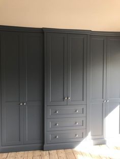 an empty room with gray cabinets and wood floors