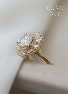 a close up view of a diamond ring on a white cloth with the words olive ave above it