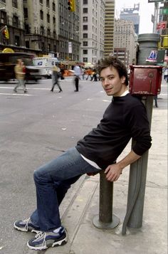 a man sitting on a pole in the middle of a city