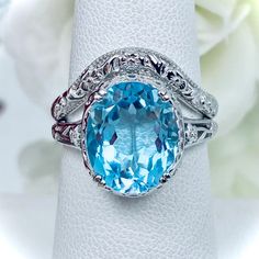 This filigree ring is an Edwardian antique reproduction in sterling silver set with a 5 carat natural light blue topaz gemstone solitaire. This faceted cut oval gem is 12mm x 10mm. This ring sits 7mm off the finger. The inside of the band is marked 925 for solid sterling silver. This ring now has a matching floral accompanying curved band. This band was specially designed to fit this ring perfect. Fine Jewelry Turquoise Topaz Ring For Anniversary, Turquoise Topaz Ring For Anniversary In Fine Jewelry Style, Turquoise Topaz Ring For Anniversary, Blue Oval Diamond Ring With Vs Clarity, Anniversary Blue Topaz Diamond Cut Ring, Oval Blue Diamond Ring With Vs Clarity, Diamond Cut Blue Topaz Ring Fine Jewelry, Silver Blue Topaz Diamond Cut Ring, Blue Topaz Diamond Cut Ring Fine Jewelry