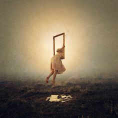 a woman hanging upside down on a ladder in the middle of a field with grass