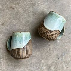 two ceramic cups sitting on top of a cement floor