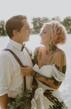 a man and woman standing next to each other in front of a body of water