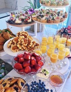 an assortment of breakfast foods and drinks on a buffet table with water in the background