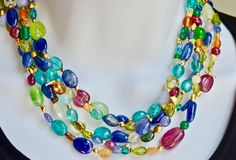 A fusion of primary and secondary colors of natural gemstone beads in this 5 strand torsade. The beads are an assortment of shapes and colors which capture the uniqueness and creativity of the necklace. Included are tourmaline, ruby, lapis, citrine, peridot, agates, sapphire, rock crystal, aquamarine The 18K yellow gold spacers  are also varied in size and shape and contribute to the singularity of the necklace. The necklace has an 18K yellow gold hook clasp closure. weight 147 grams. Elegant Multicolor Multi-stone Beaded Necklace, Multicolor Multi-stone Beads And Cabochons For Jewelry Making, Multicolor Multi-stone Beads For Jewelry Making, Elegant Double Strand Multicolor Beads, Elegant Multi-color Double Strand Beads, Elegant Multicolor Polished Gemstone Beads, Elegant Multicolor Double Strand Beads, Elegant Multicolor Gemstone Beads, Multicolor Gemstone Beaded Necklace In Fusion Style