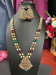 Lord Balaji Pendent/ Maroon Red and Gold Beads Haram/Gold Finish AD Stones 2 Lines Each Side/32 inches Long /Handmade /South Indian Jewelry DETAILS: Includes One  Haram and Two Earrings. Necklace: 26.4 inches.total 30 inches Adjustable length total Chain closure. Weighs 3.00oz ( 85g).  Earrings: 2.1 inch(es) long. Earring set weighs 0.60 oz (17 g). Earring backs push on/off. Material: Imitation, Gold Finish ,Pearls CZ  AD Stones. Finish: Gold finish Pendent with Beads. NOTE: I try my best to show you photos of my products as they appear in real life, but please note that variations in color occur due to differences in lighting and screen settings.  PRODUCT CARE: - Avoid contact with heat/fire, water, and chemicals such as perfumes or any sprays to prevent product damage.  - Store wrapped i Red Pearl Necklace Temple Jewelry For Festivals, Red Pearl Temple Jewelry Necklace For Festivals, Red Temple Jewelry Pearl Necklace For Festivals, Festive Long Necklace With Colorful Beads, Festive Celebration Necklace With Beaded Chain, Traditional Red Beaded Pearl Necklace, Festive Beaded Chain Necklace For Celebrations, Festive Long Beaded Necklace With Colorful Beads, Festive Celebration Beaded Chain Necklace