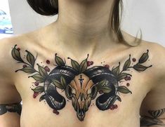 a woman with tattoos on her chest has an animal skull and leaves in the center