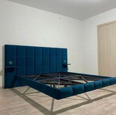 a blue bed frame sitting on top of a hard wood floor in an empty room