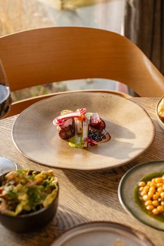 a wooden table topped with plates and bowls filled with different types of food on top of it