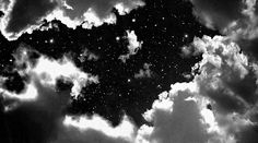 black and white photograph of clouds in the night sky with stars on it's left side