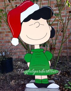 a cardboard charlie brown christmas decoration in front of a brick wall