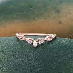 a close up view of a wedding ring with pink stones on the top and bottom