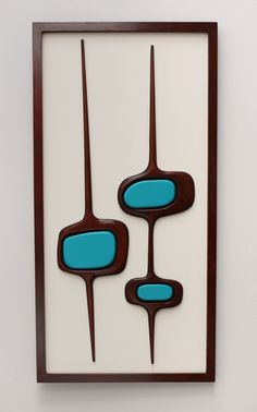 an art piece hanging on the wall with blue and brown shapes in front of it