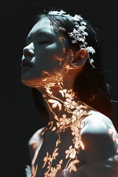 a woman with flowers on her neck is lit up by the light of a candle