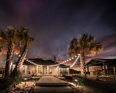 palm trees are lit up in front of a house