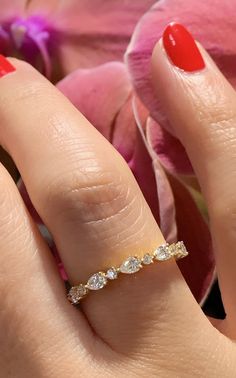 a woman's hand with a diamond ring on it and flowers in the background