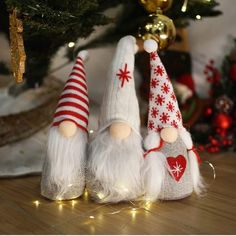 three christmas gnomes sitting next to a christmas tree