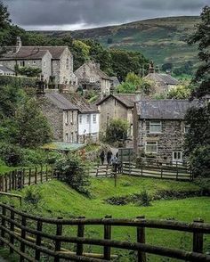 the village is surrounded by lush green hills and trees, with houses in the background