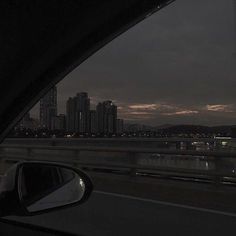 the view from inside a car looking out at a river and cityscape in the distance