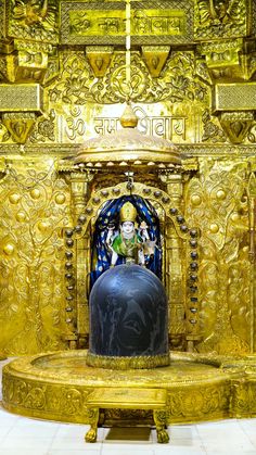 an elaborately decorated gold alter with a large vase in the center and two statues on either side