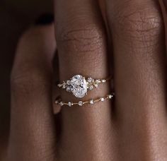 a woman's hand with a diamond ring on top of her finger and an engagement band